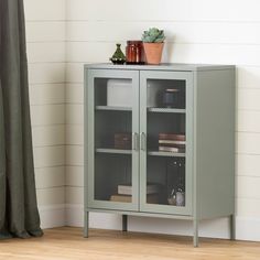 a green cabinet sitting next to a window with a potted plant on top of it