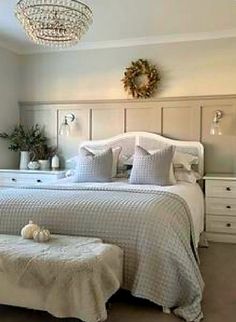 a bedroom with a bed, dressers and a chandelier