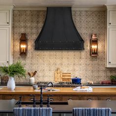 a kitchen with an oven and two chairs in front of the counter top, along with potted plants