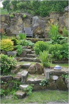 a garden with rocks, plants and a bench