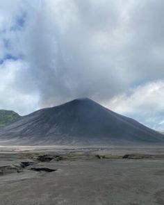 there is a mountain in the distance with rocks on the ground and grass around it