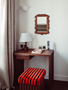 a desk with a mirror, lamp and stool