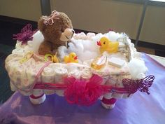 a teddy bear sitting in a baby's cradle with rubber ducks and diapers