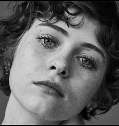 a black and white photo of a woman with freckles on her face looking at the camera