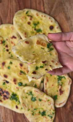 a hand holding up a tortilla on top of a wooden table