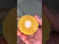 a person is holding a yellow pastry in their left hand and the other hand has a white substance on it