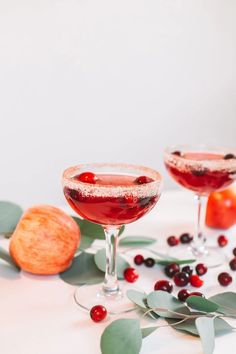 two wine glasses filled with cranberry shrub martinis and garnished with leaves