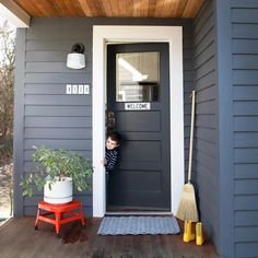 a little boy standing at the front door of a house