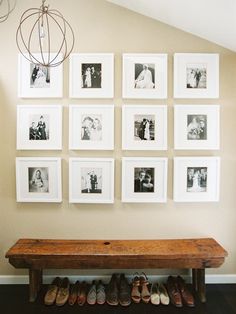 a wooden bench sitting in front of a wall with pictures on it and shoes underneath