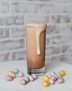 a glass filled with some kind of drink next to small candy candies on a table