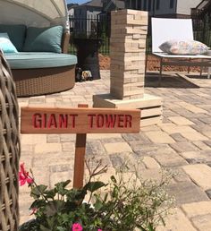 a wooden sign that says giant tower on the side of a brick patio next to a flower pot