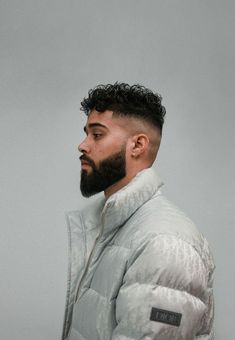 a man with a beard wearing a white puffy jacket and looking off to the side