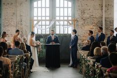 a bride and groom stand at the alter during their wedding ceremony in an old warehouse