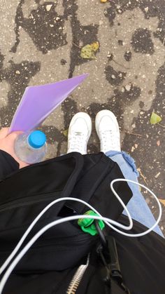 a person with their feet on the ground holding an object in one hand and wearing white shoes