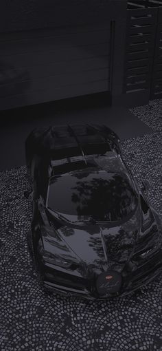 a black sports car parked in front of a garage with its hood up and lights on