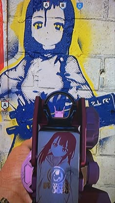 a person holding a cell phone in front of a graffiti wall with a girl on it