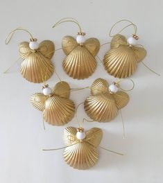 six gold seashells with pearls hanging from the side on a white background,