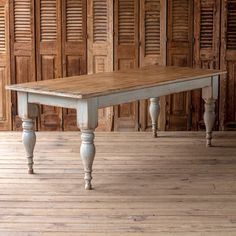 an old wooden table sitting on top of a hard wood floor next to shutters