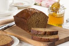 sliced loaf of bread sitting on top of a cutting board next to a jar of honey