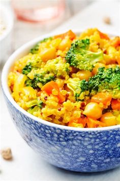 a bowl filled with broccoli and carrots on top of a white table