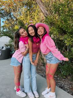 three girls in pink shirts and cowboy hats posing for the camera with their arms around each other