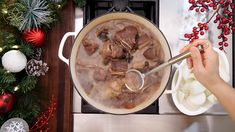 a person stirring food in a pot on top of a stove next to christmas decorations