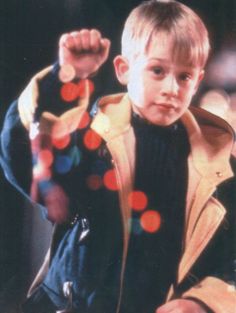 a young boy wearing a jacket and holding his fist up