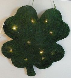 a piece of green yarn with lights on it hanging from a hook in the shape of a leaf