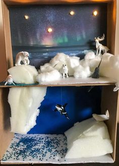 an orca whale and other animals are on display in a cardboard box with snow