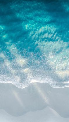 an aerial view of the ocean waves and sand