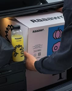 a person opening the back of a box with a yellow water bottle in front of it