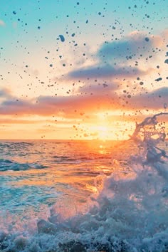 the sun is setting over the ocean with water splashing on it