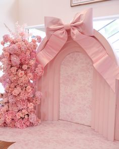 a pink arch with flowers and a bow on it