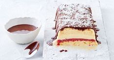 a piece of cake sitting on top of a table next to a bowl of chocolate