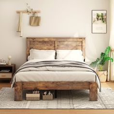 a bed sitting on top of a wooden floor next to a wall mounted potted plant