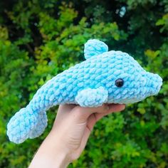 a hand holding a blue crocheted stuffed animal