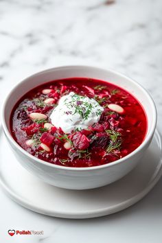 a white plate topped with a bowl of soup and sour cream on top of it