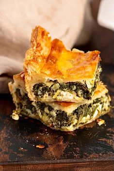 three pieces of quiche stacked on top of each other with cheese and spinach