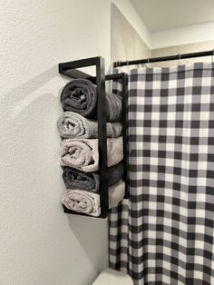 towels are hanging on a towel rack next to a shower curtain in a white and black bathroom