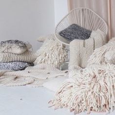 a pile of blankets and pillows sitting on top of a white floor next to a window