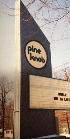 the sign for pine knob is in front of a building with a clock on it