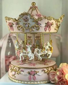 there is a pink and gold carousel with horses on the top, next to flowers