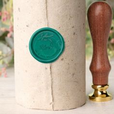 a green wax stamp sitting on top of a white container next to a wooden handle