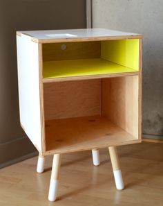 a small white and yellow shelf sitting on top of a hard wood floor