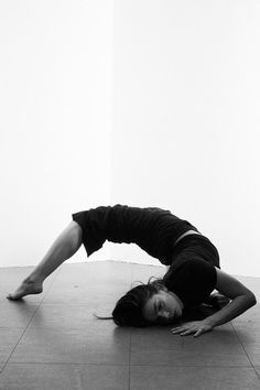 a woman is doing yoga on the floor with her hands behind her head and legs bent forward