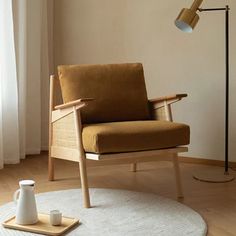 a brown chair sitting on top of a wooden floor next to a white rug and lamp