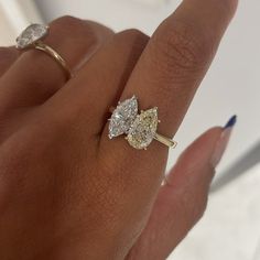 a woman's hand with two engagement rings on it and one diamond ring in the middle