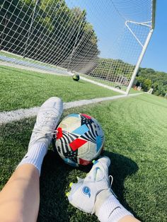 a person's feet resting on the ground next to a soccer ball