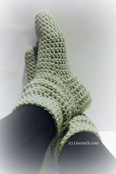 a pair of green crocheted gloves sitting on top of a table