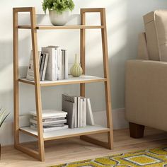 a wooden shelf with books and magazines on it next to a couch in a living room